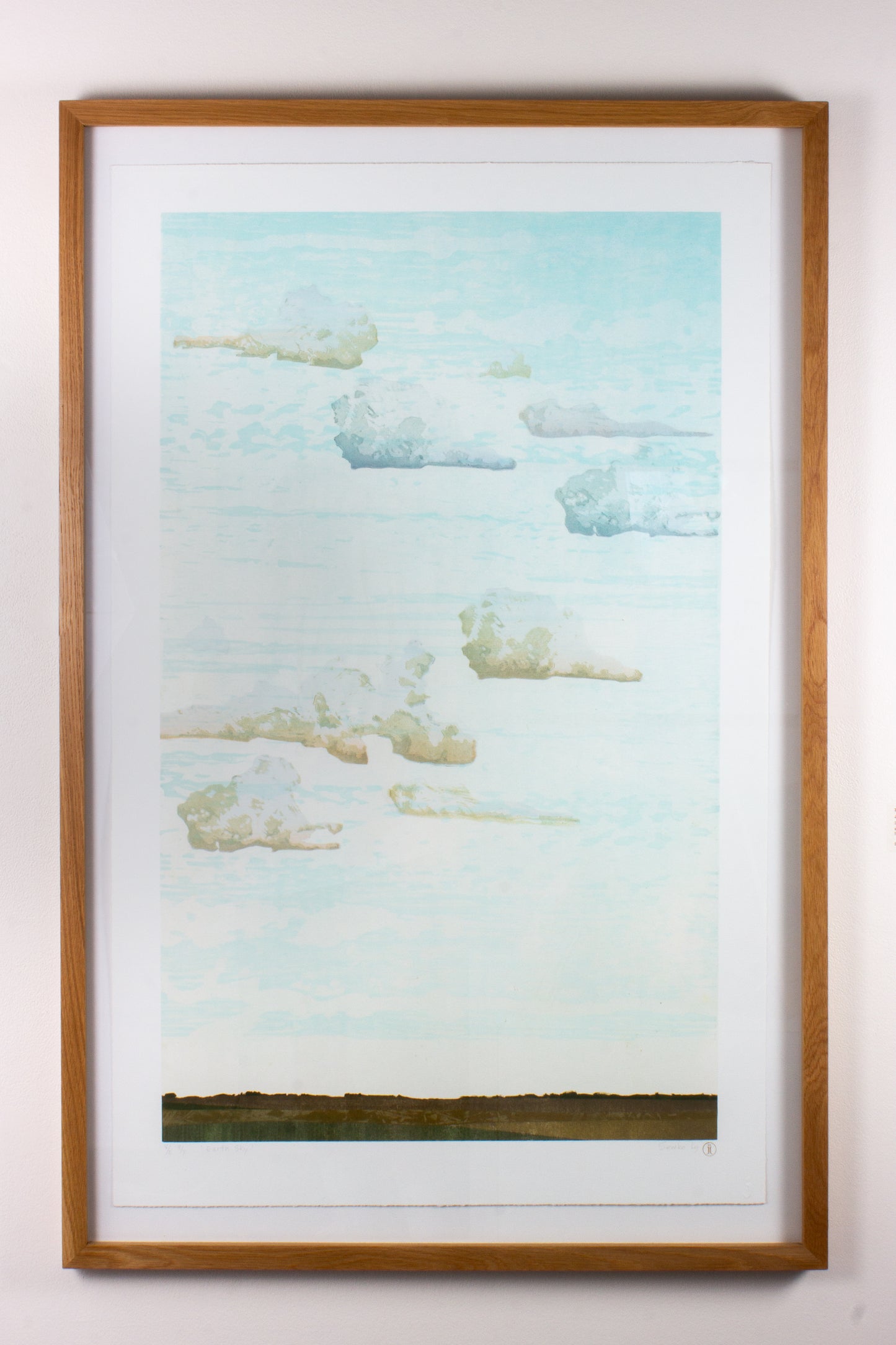 Framed wood print of a landscape with a blue sky and green field.