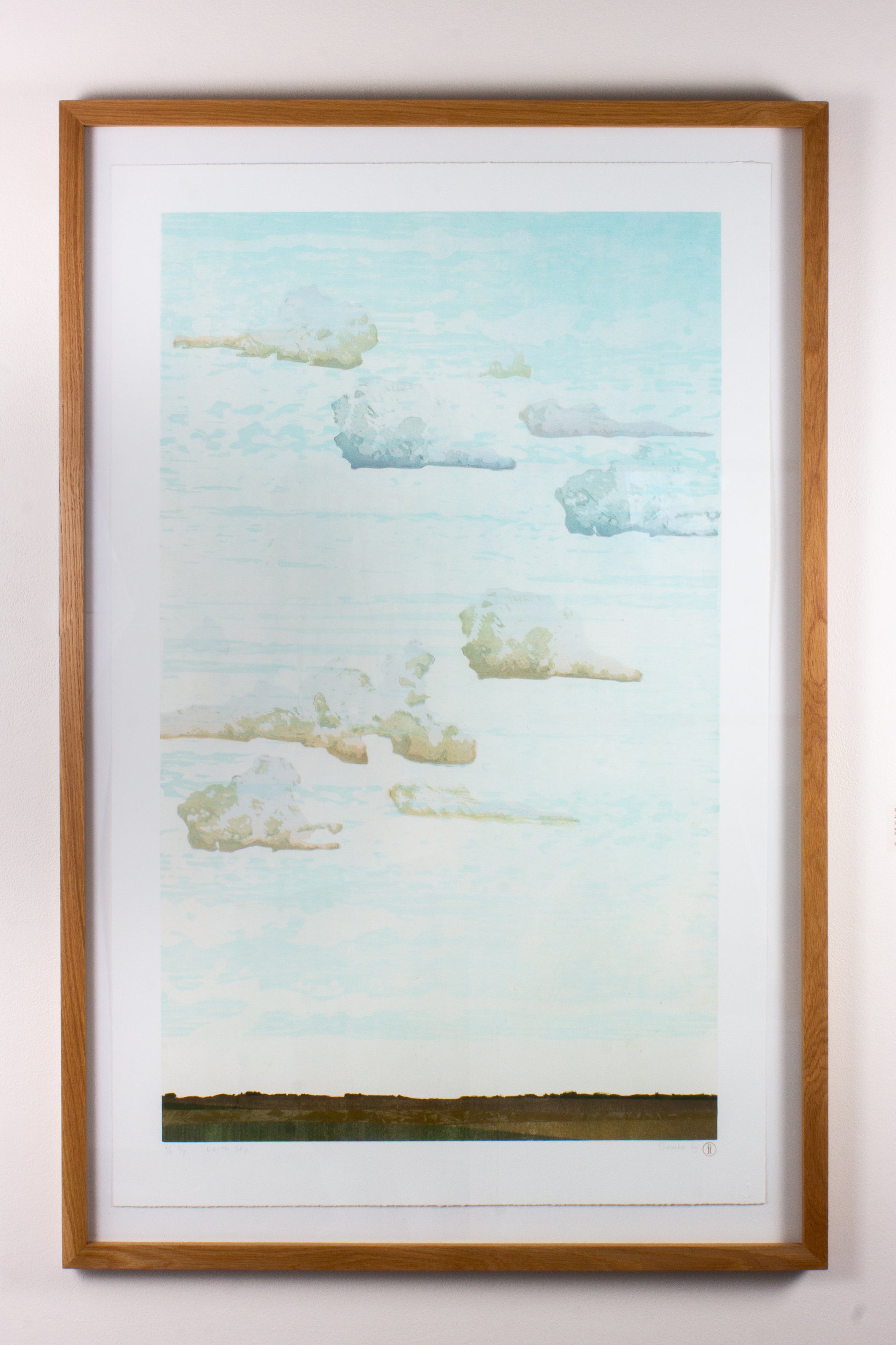 Framed wood print of a landscape with a blue sky and green field.