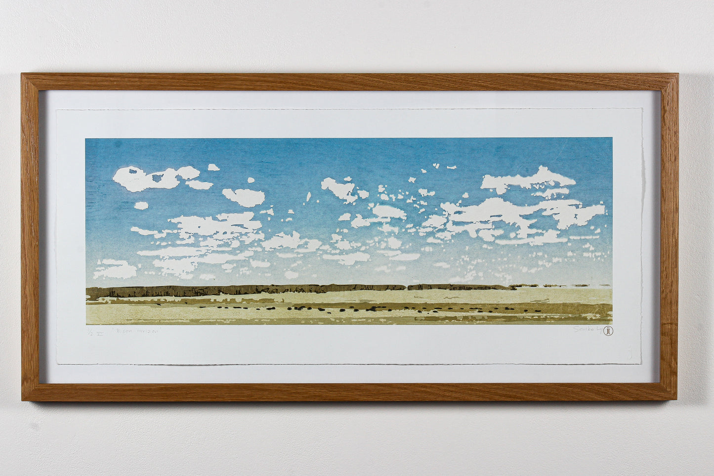 Framed wood print of a landscape with blue sky and white clouds