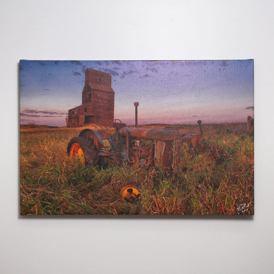 Photograph of an abandoned grain elevator and overgrown tractor
