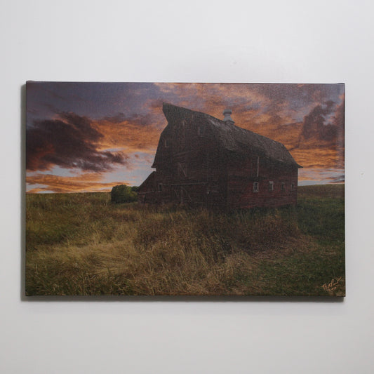 Photograph of dilapidated barn in front of a sunset