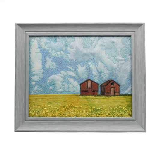 Embroidered scene of a prairie canola field with two granaries 