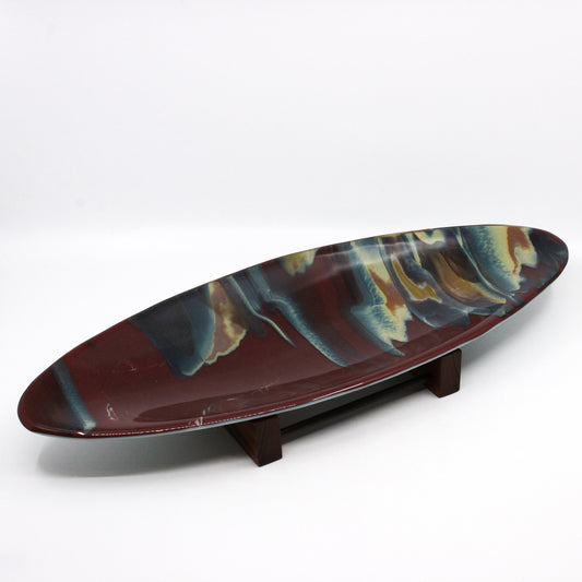 Burgundy plate marbled with dark blue and ochres on a stand
