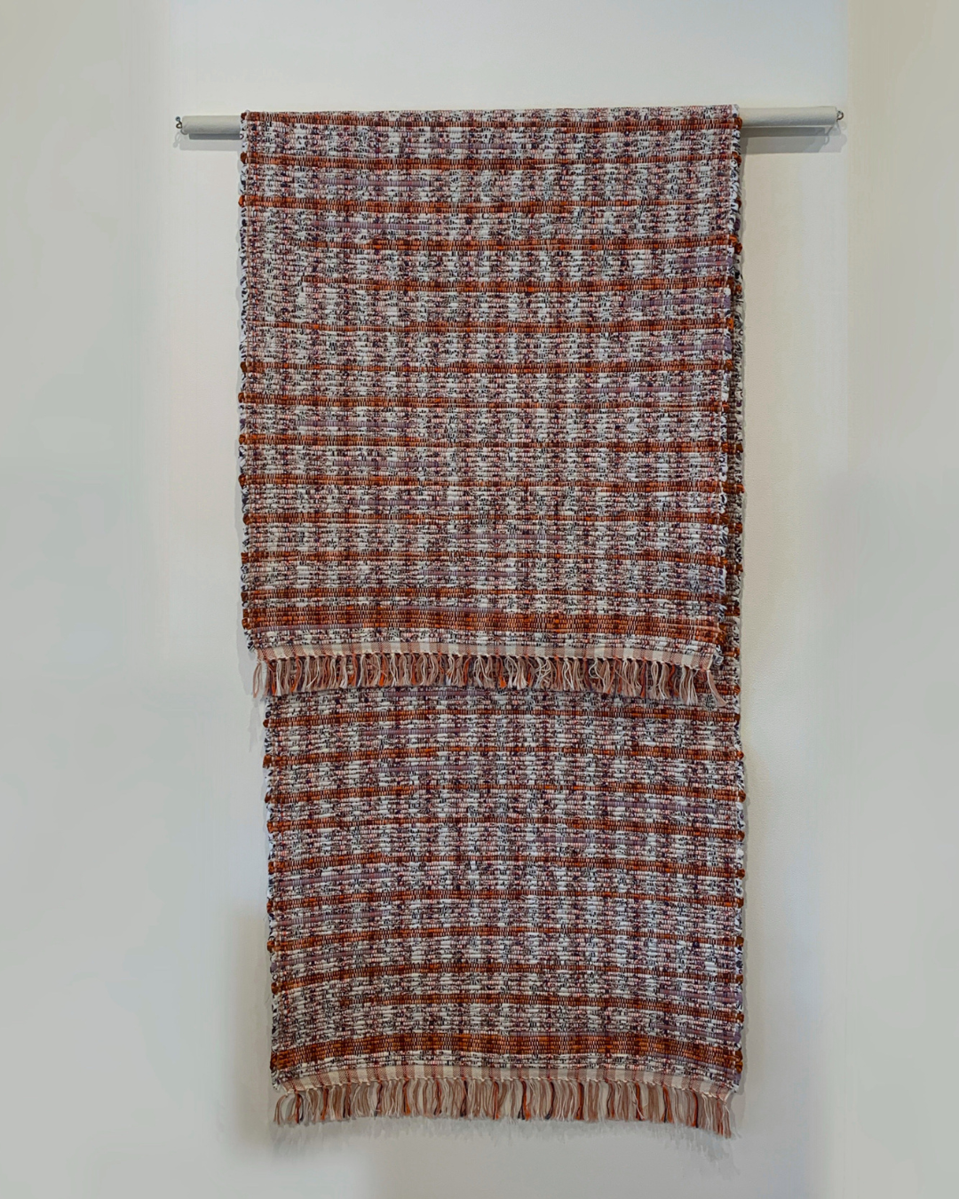 Red and white check rug with fringe hanging over a bar