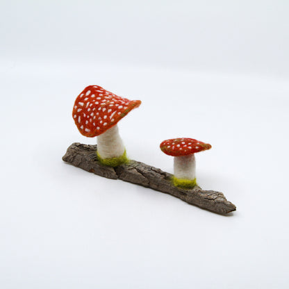 Two felted mushrooms on a piece of driftwood