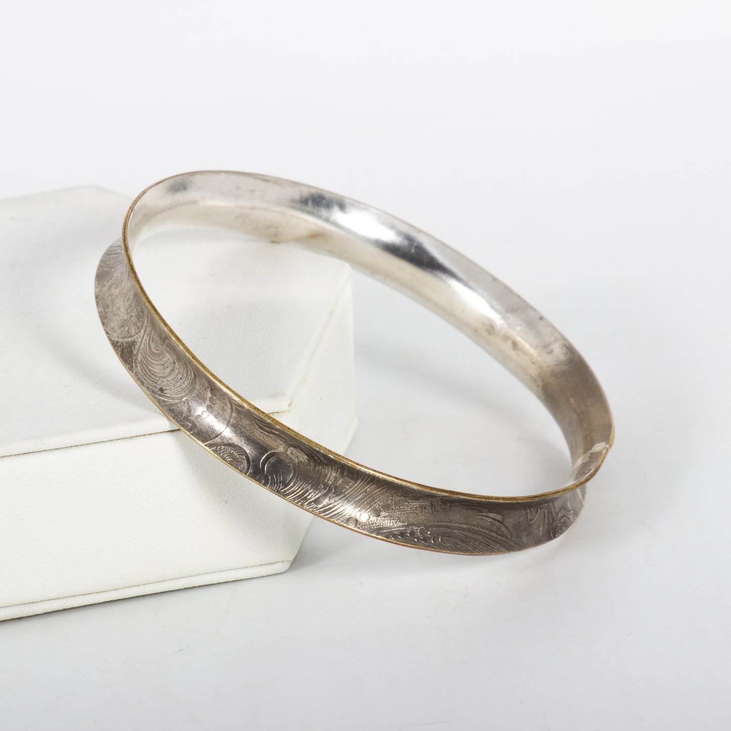 Silver bracelet with engraved design on a white surface