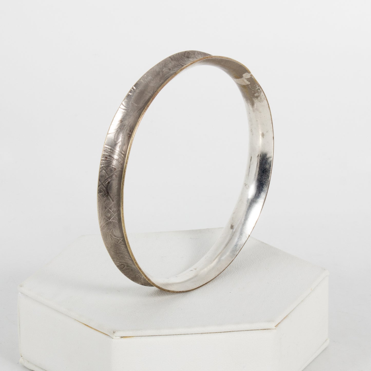Silver ring with a textured band on a white background