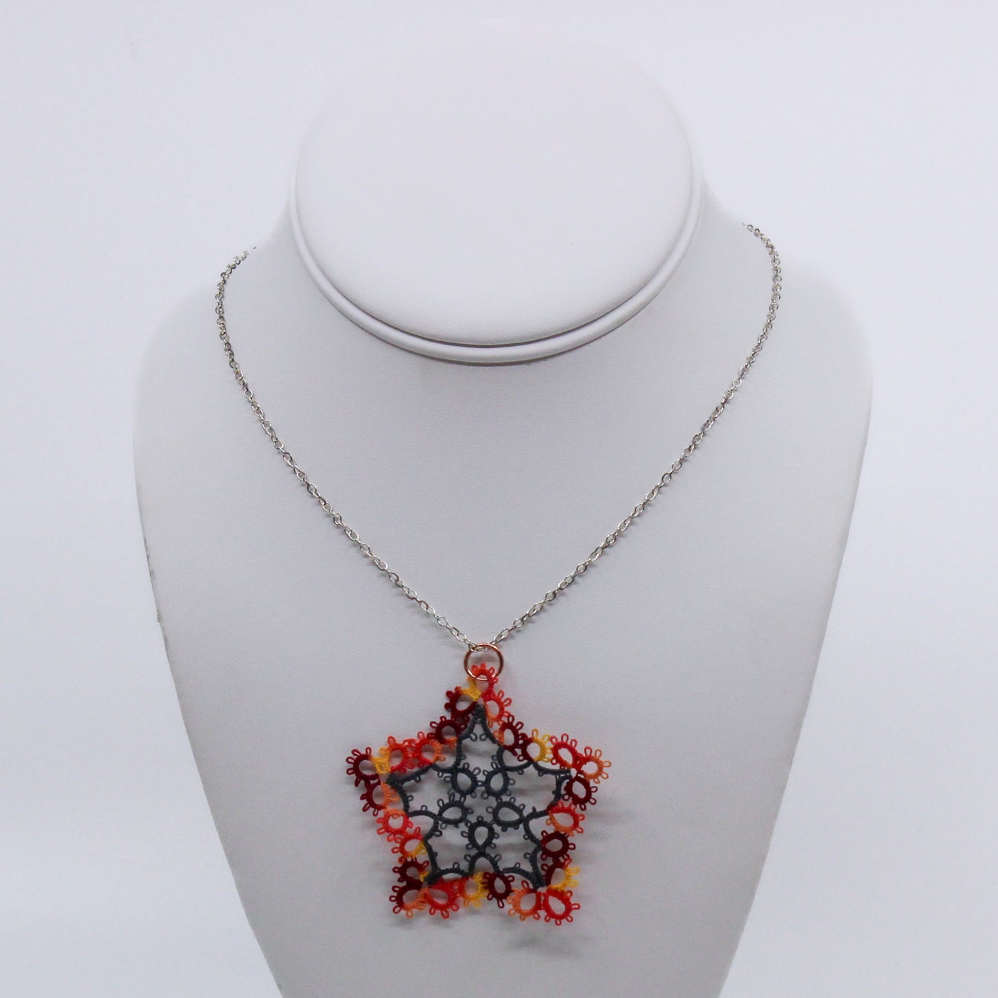 hand wove doily of a flower in red, yellow, and orange