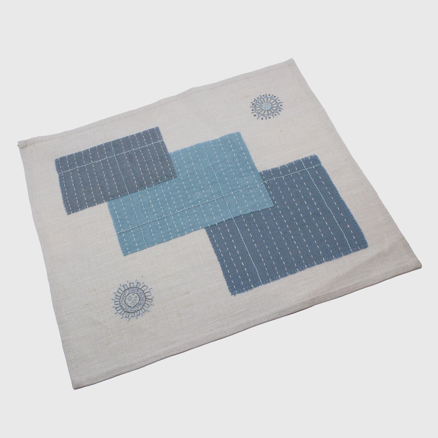 Embroidered table mat with stitched rectangles and mandalas