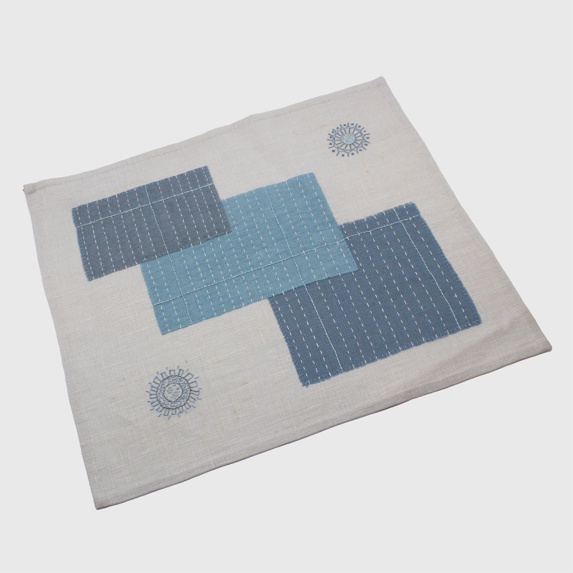Embroidered table mat with stitched rectangles and mandalas