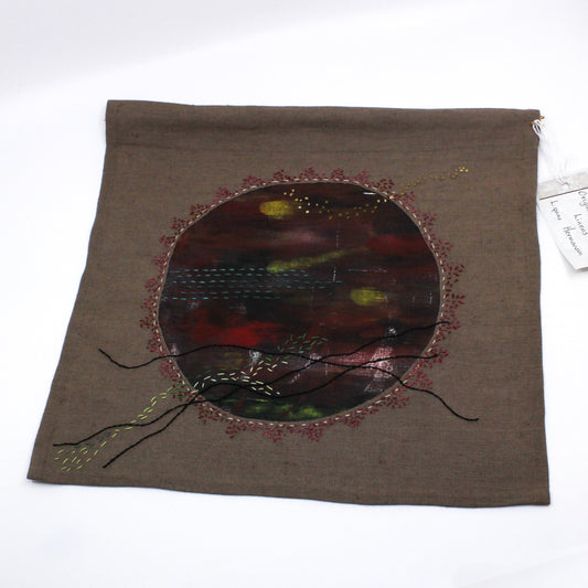 Wall hanging of a red circle with hand stitching