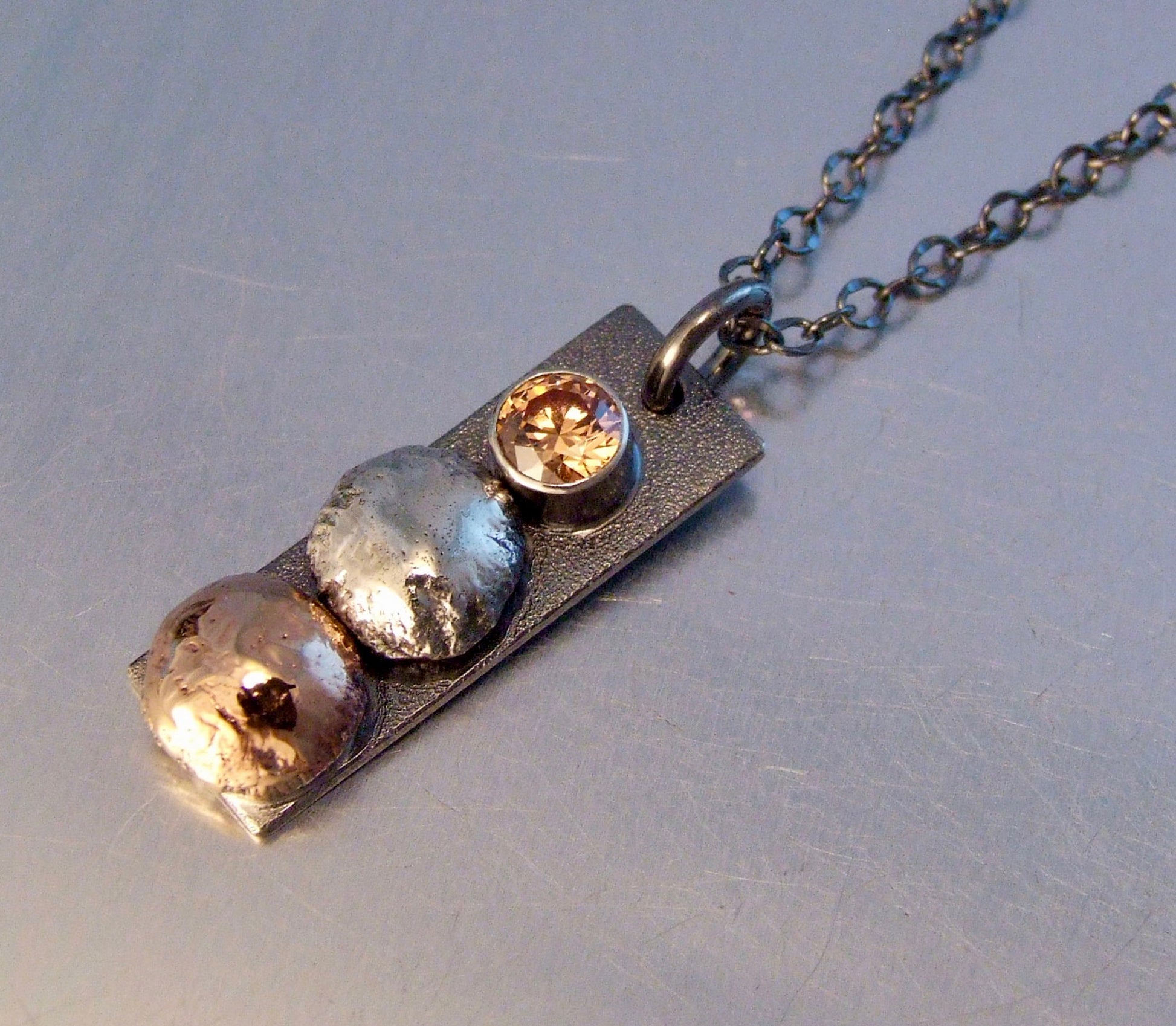 Rectangle pendant with stacked bronze, silver, and zirconia