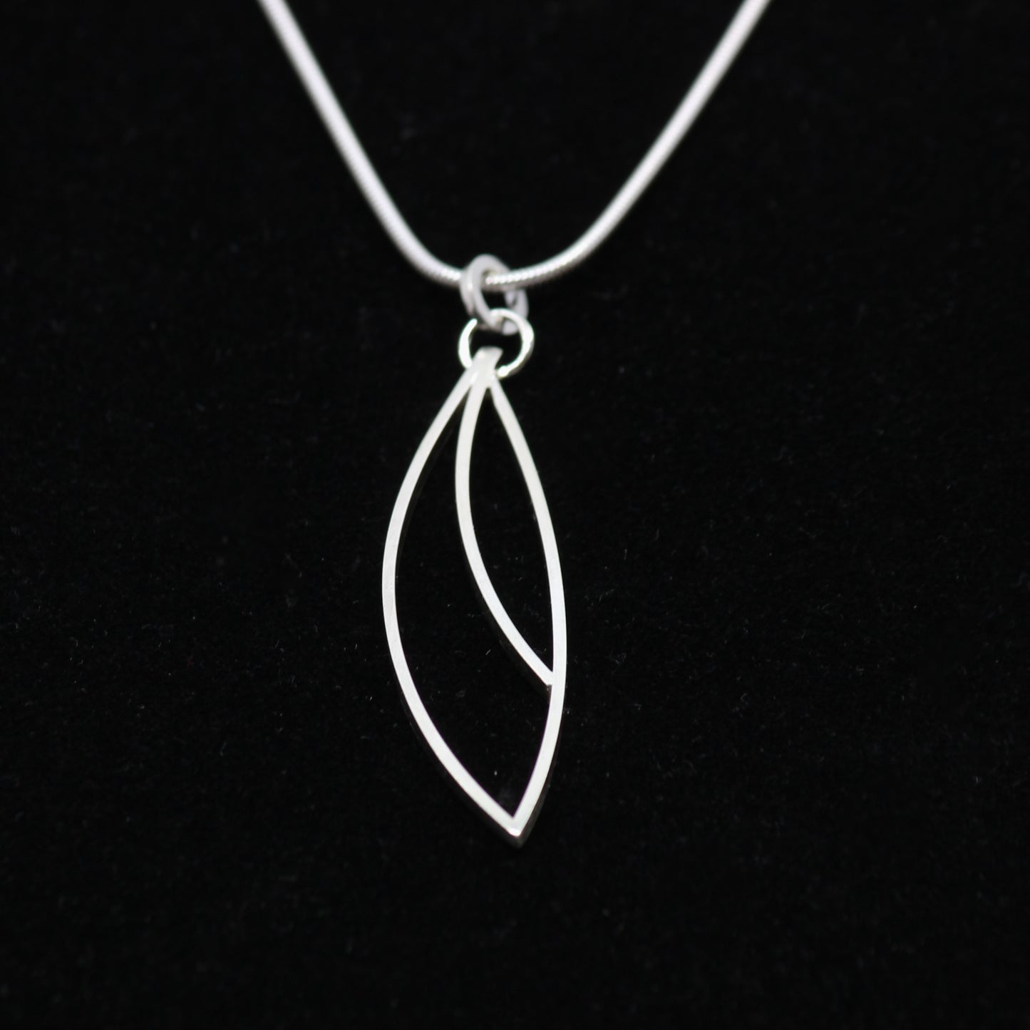 Silver leaf-shaped pendant on a black background