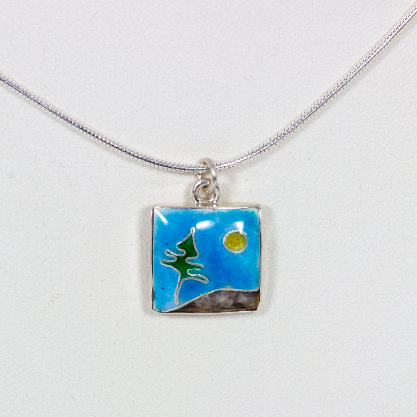 Necklace with a square pendant featuring a landscape design on a white background