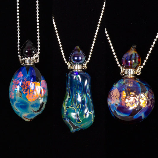 Three colorful glass pendants on chains against a black background