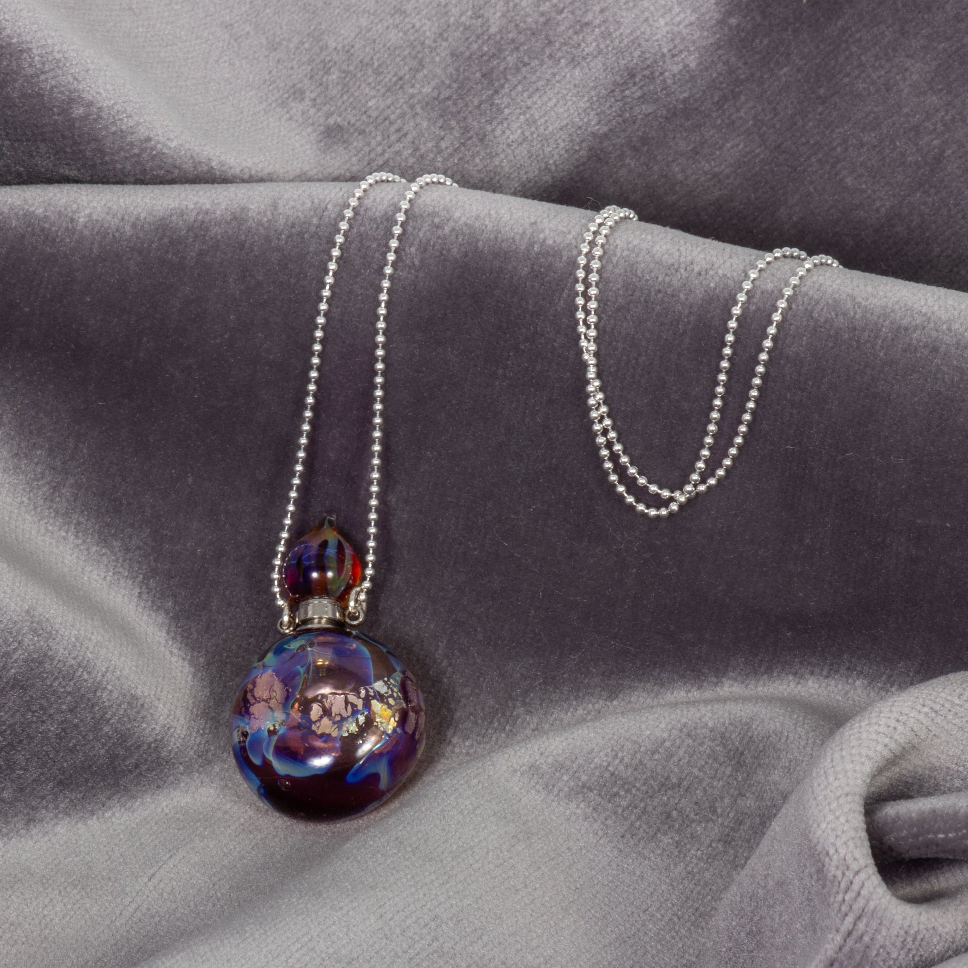 Necklace with a colorful pendant on a gray fabric background