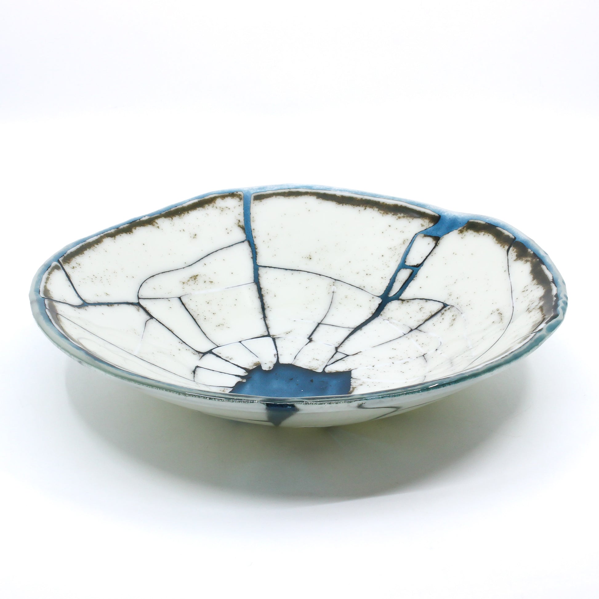 Cracked opaque white bowl filled in with transparent blue glass