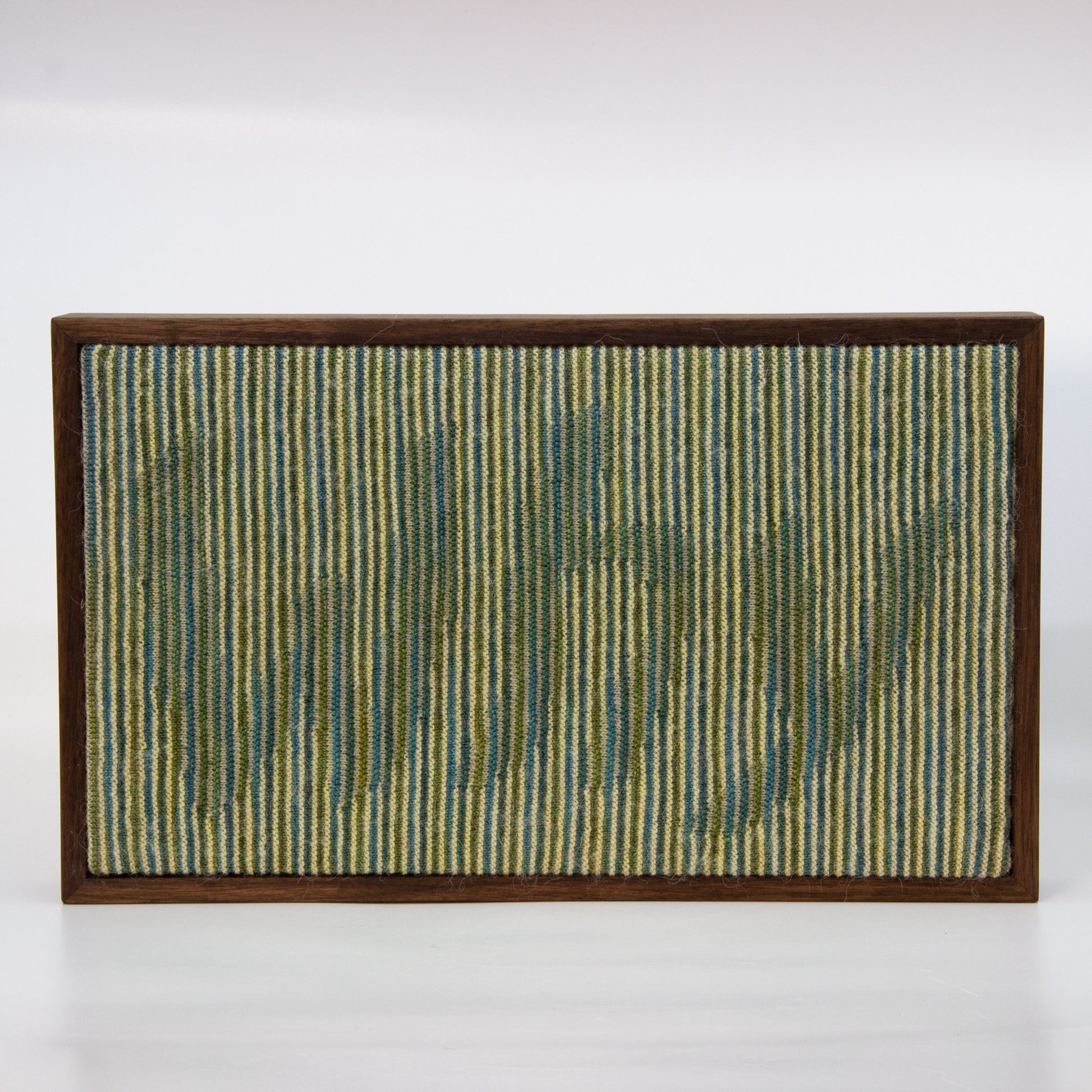 Binary knitted wall hanging with cream blue and green yarn. Text: Why