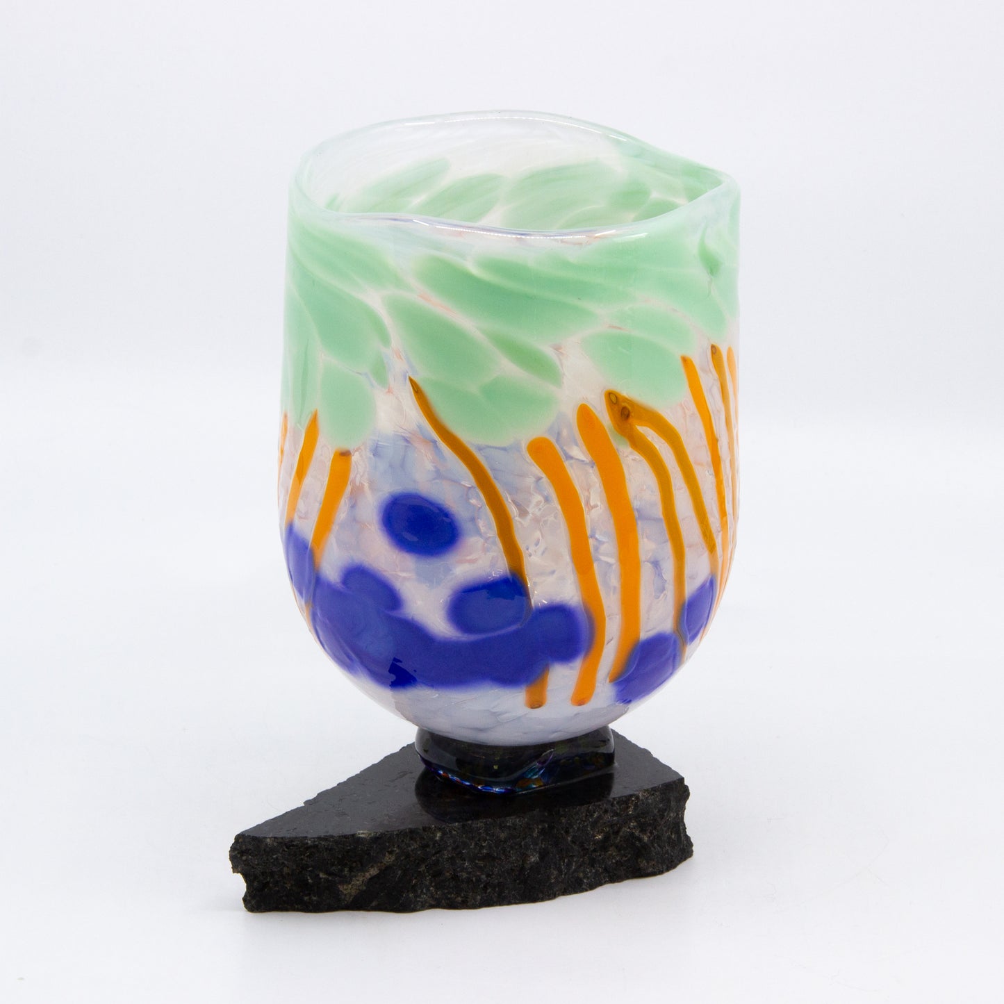 Tall glass bowl of coloured glass mounted on rock