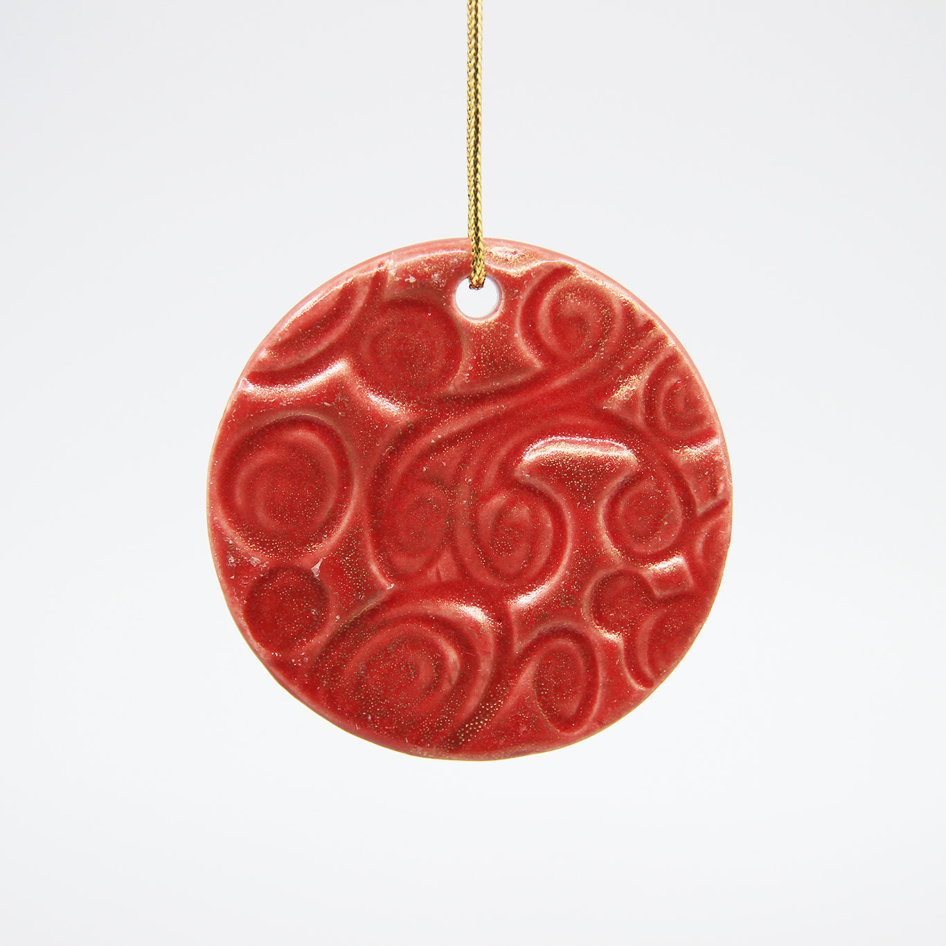 Red circle clay Christmas ornament with carved pattern and dusted with gold