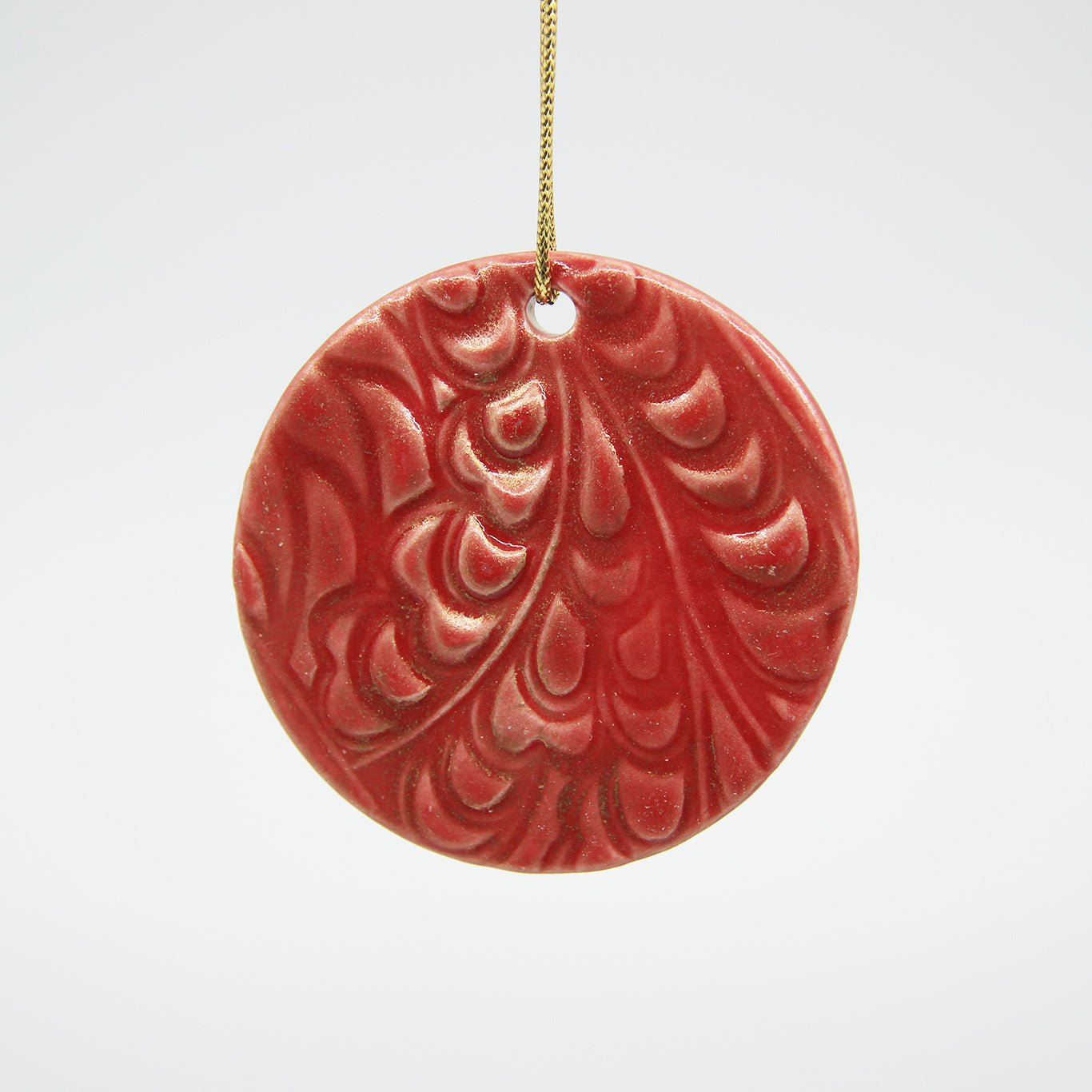 Red circle clay ornament with carved pattern and dusted with gold lustre