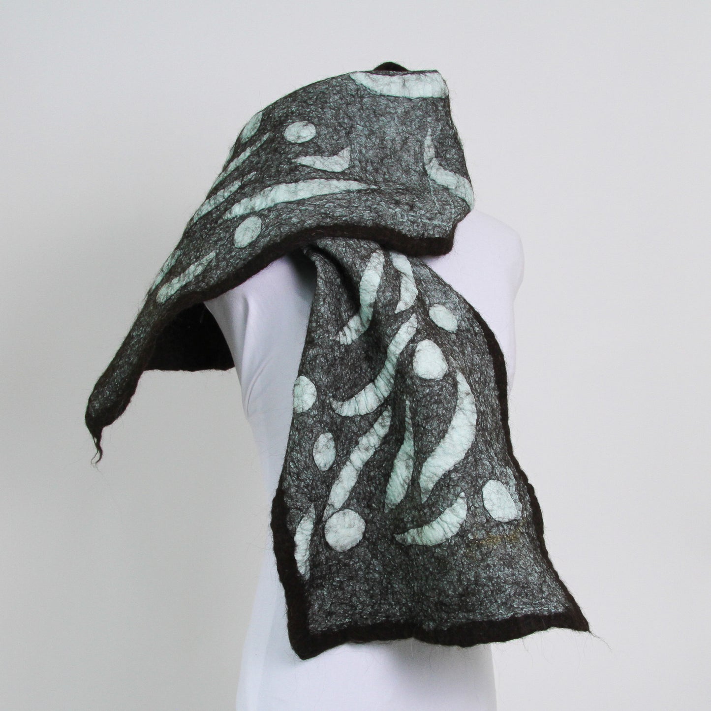 Teal scarf with abstract shapes trimmed with dark brown.