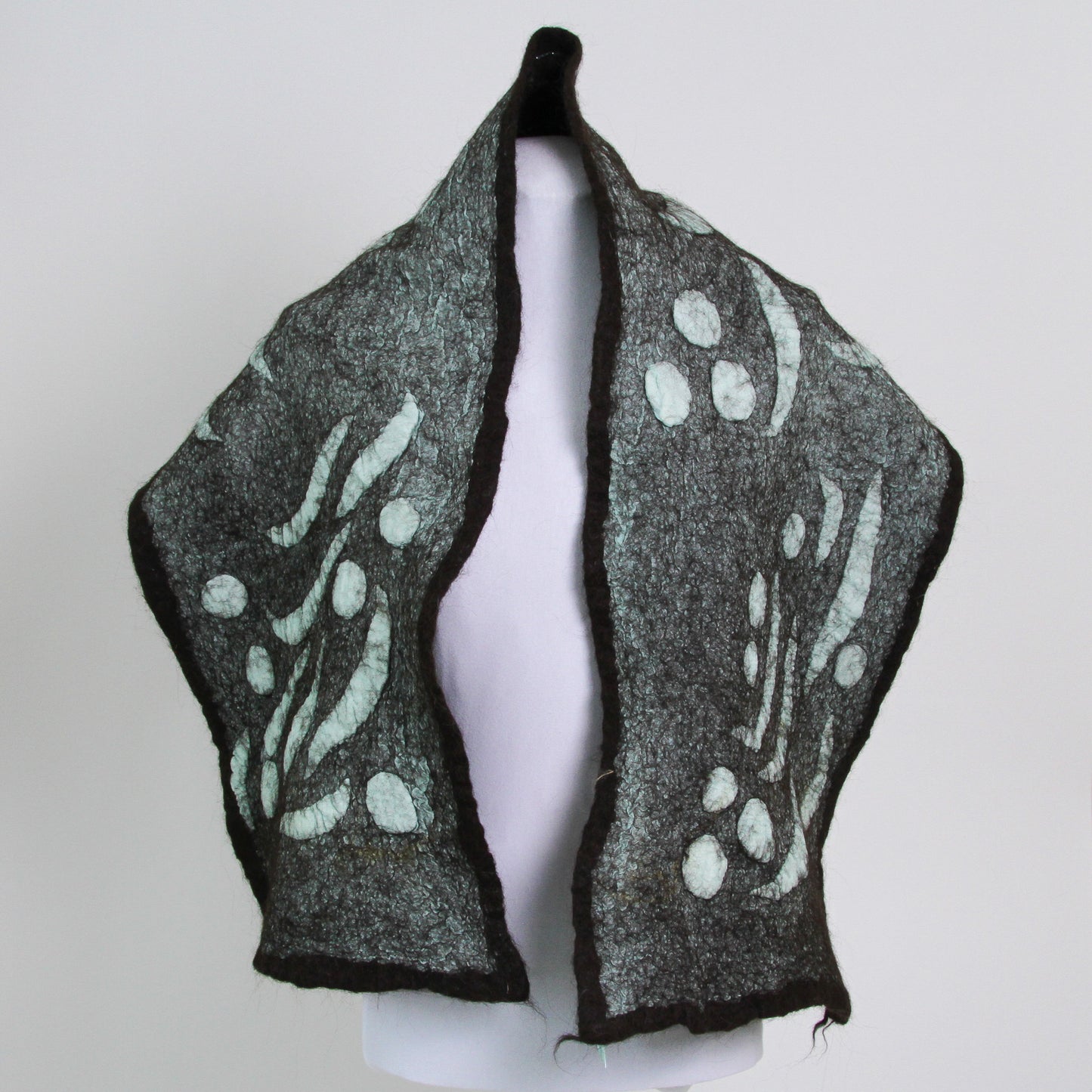 Teal scarf with abstract shapes trimmed with dark brown.