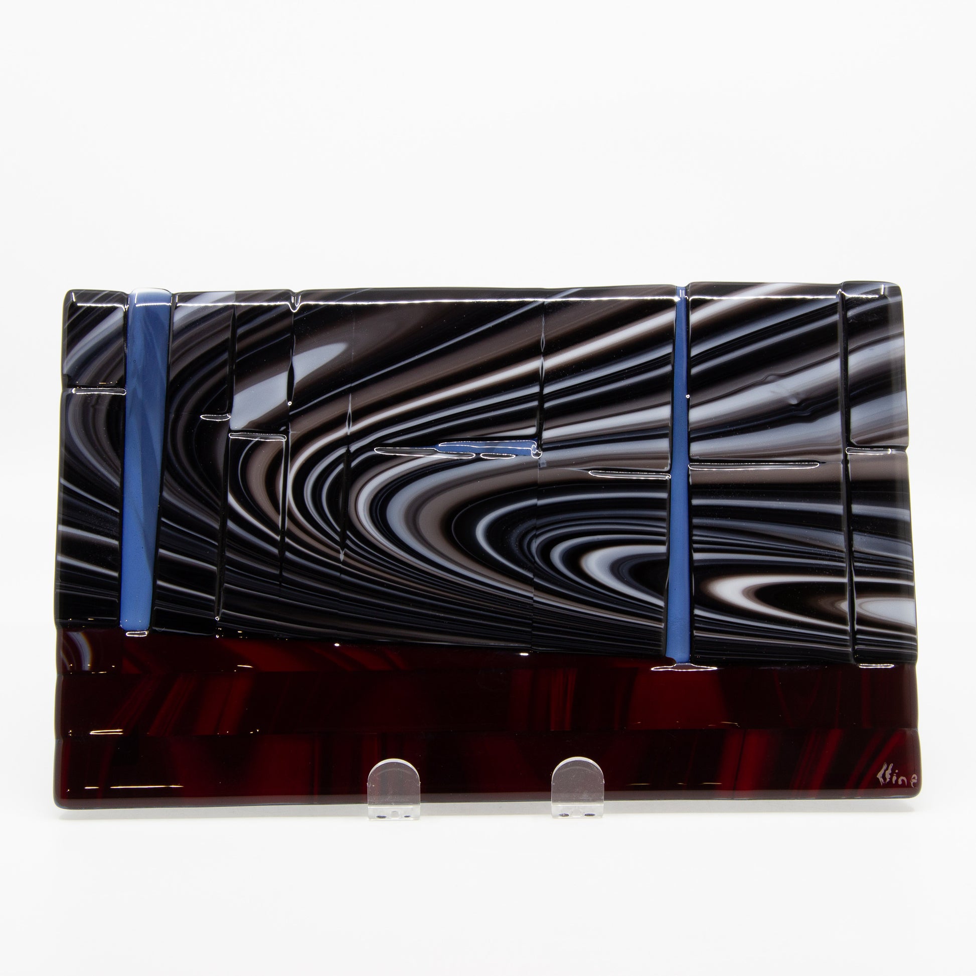 Glass tablet of a swirly sky above a red ground with blue streaks