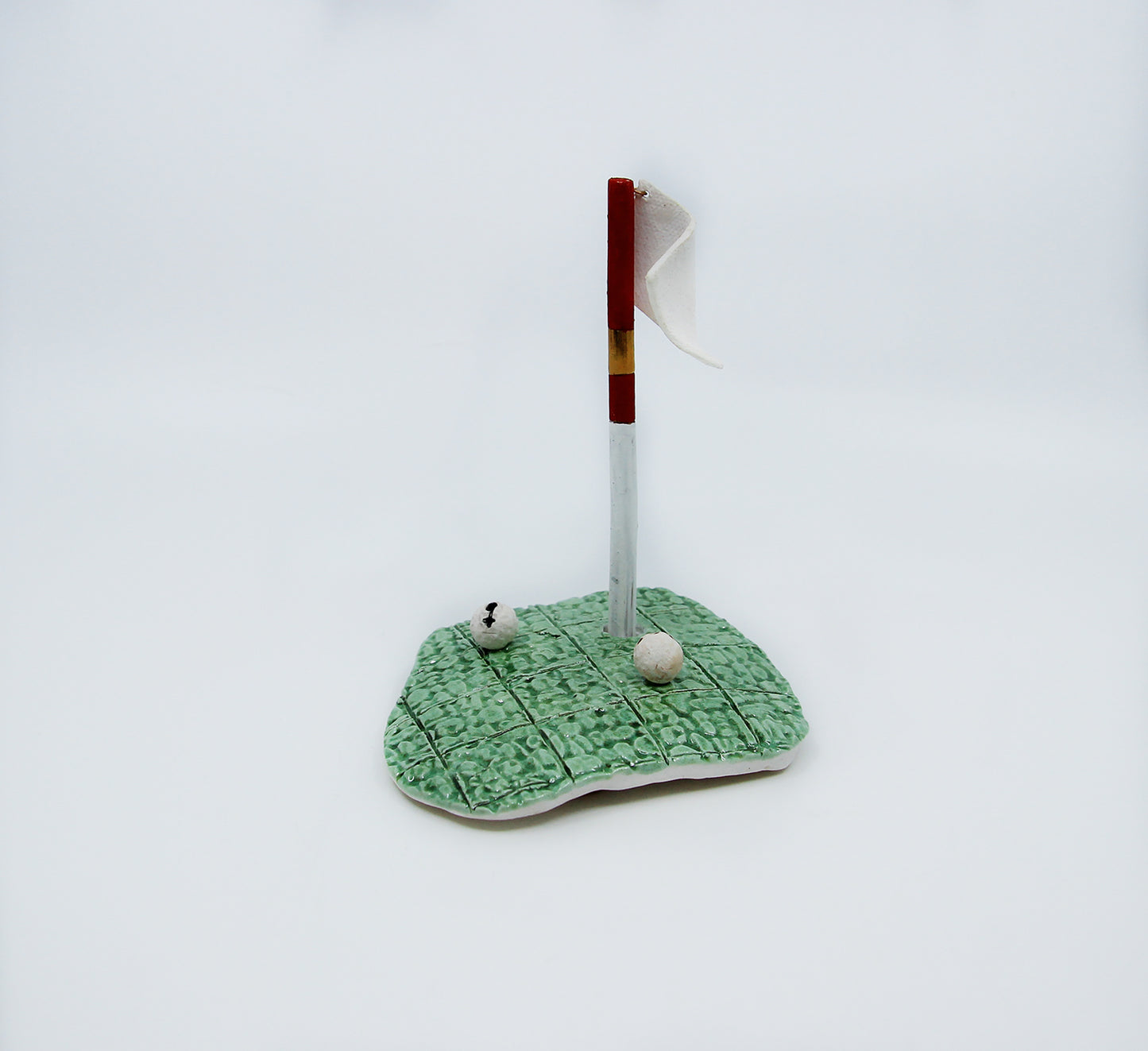 Clay golf green with red flag and two golf balls