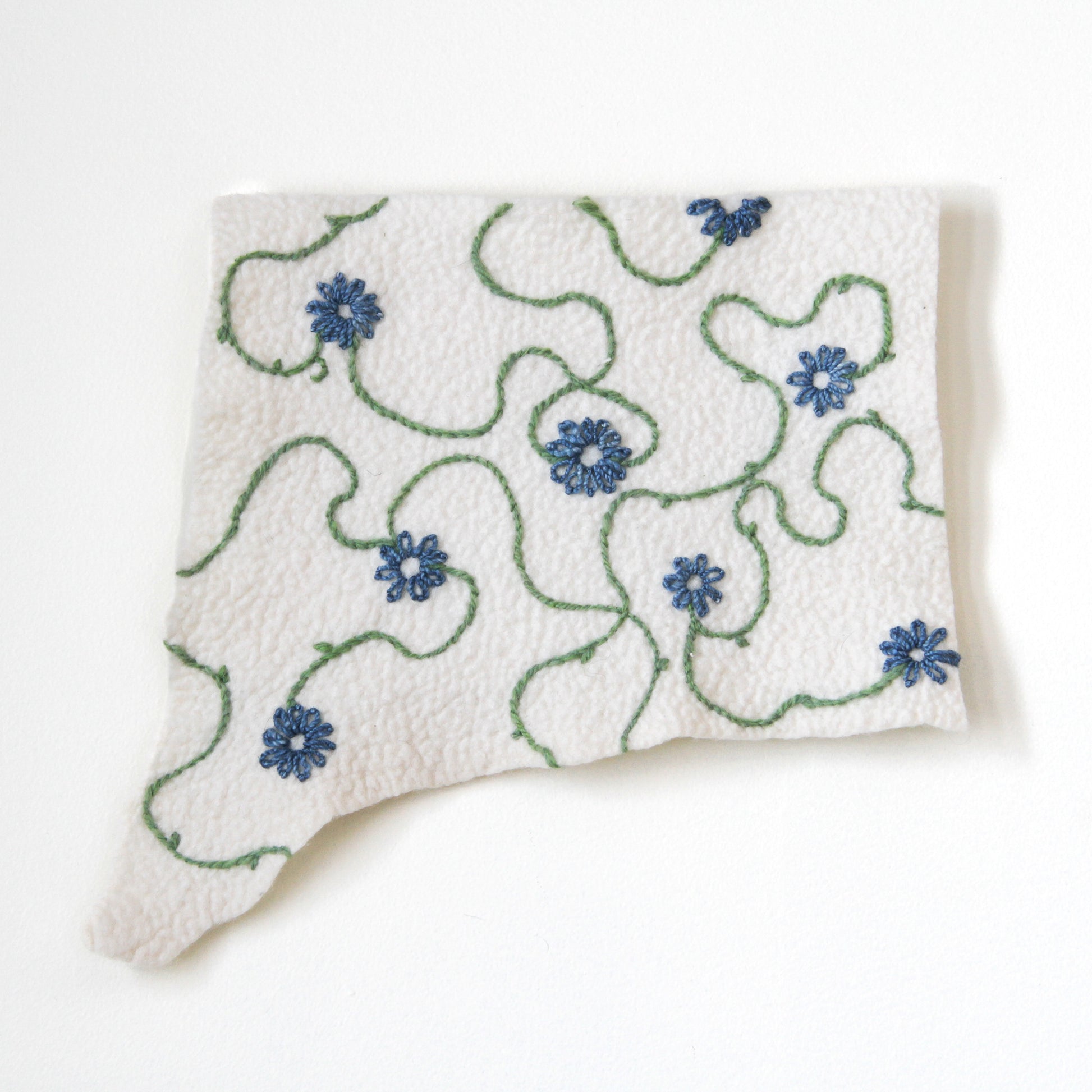 Felted wall hanging embroidered with blue flowers and green vines