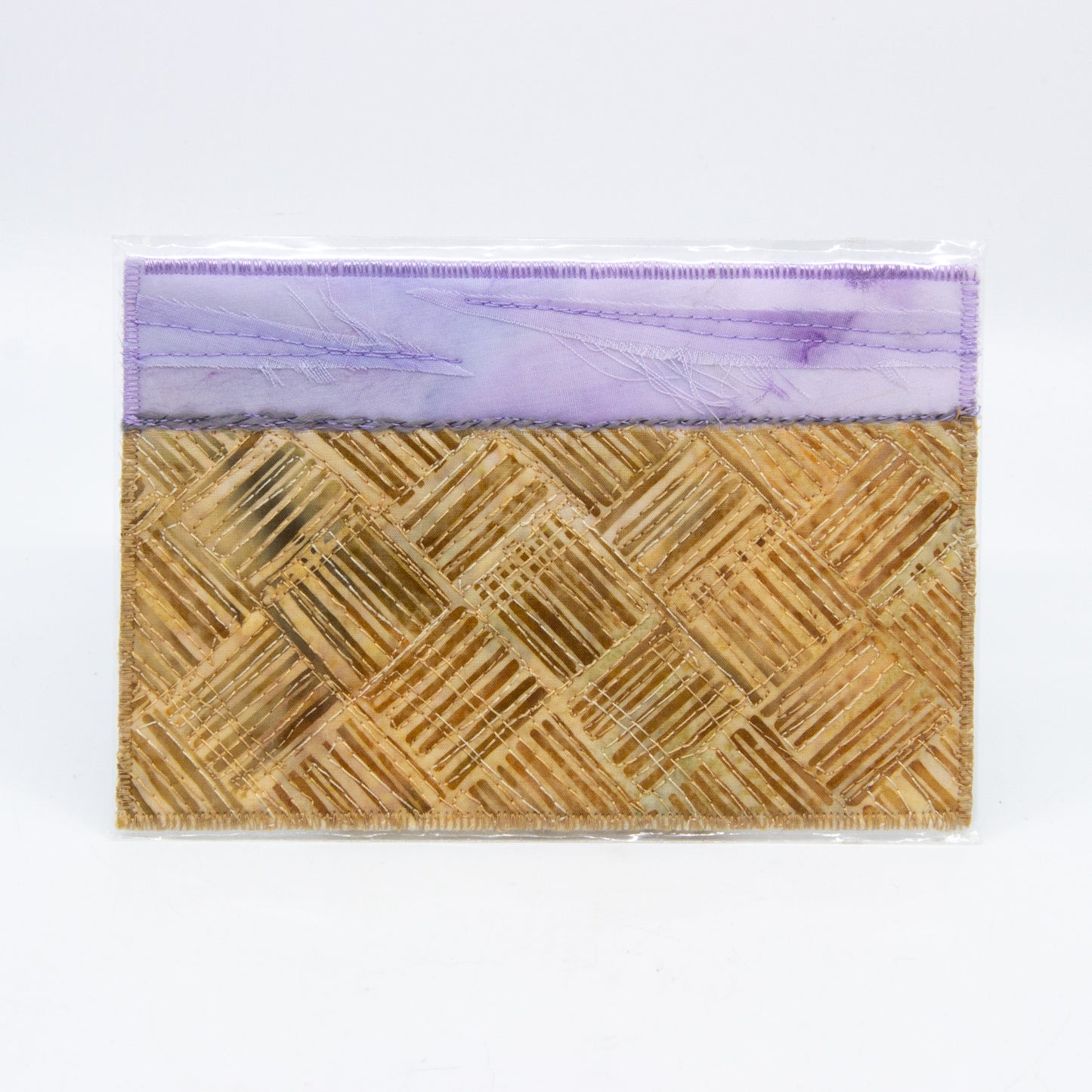 Mini art quilt of a prairie: purple sky and brown hatched fields