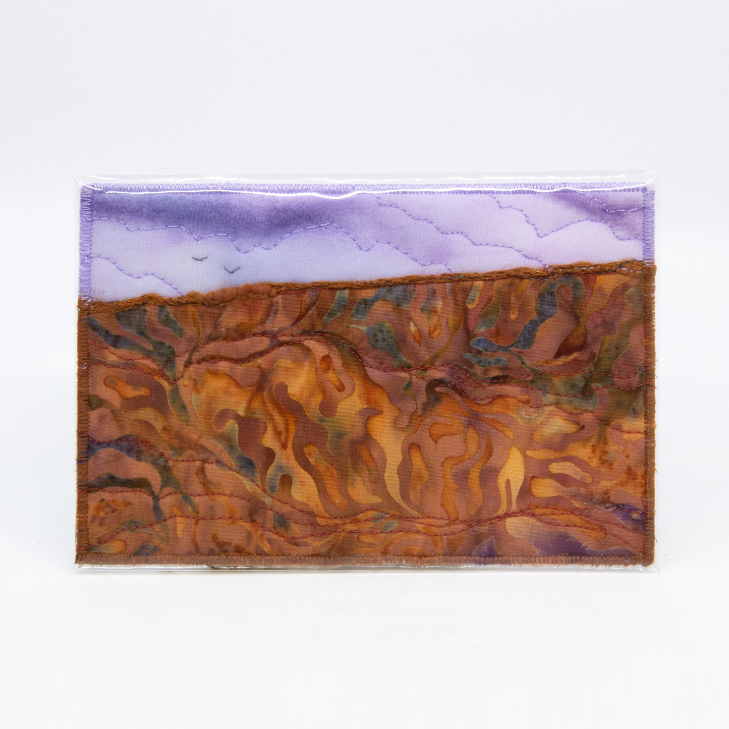 Mini art quilt of a prairie: purple sky with birds,  brown fields with dyed patterns