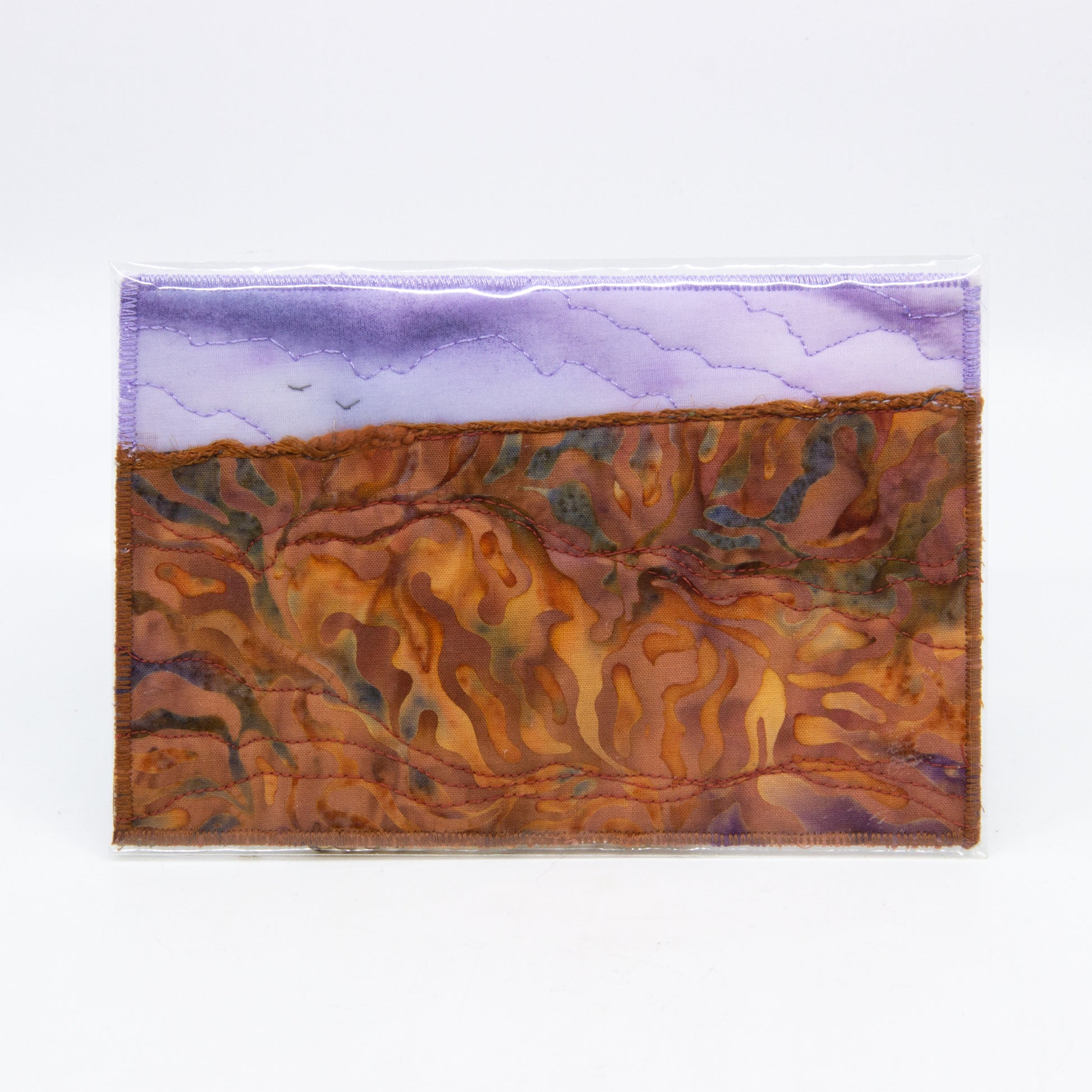 Mini art quilt of a prairie: purple sky with birds,  brown fields with dyed patterns