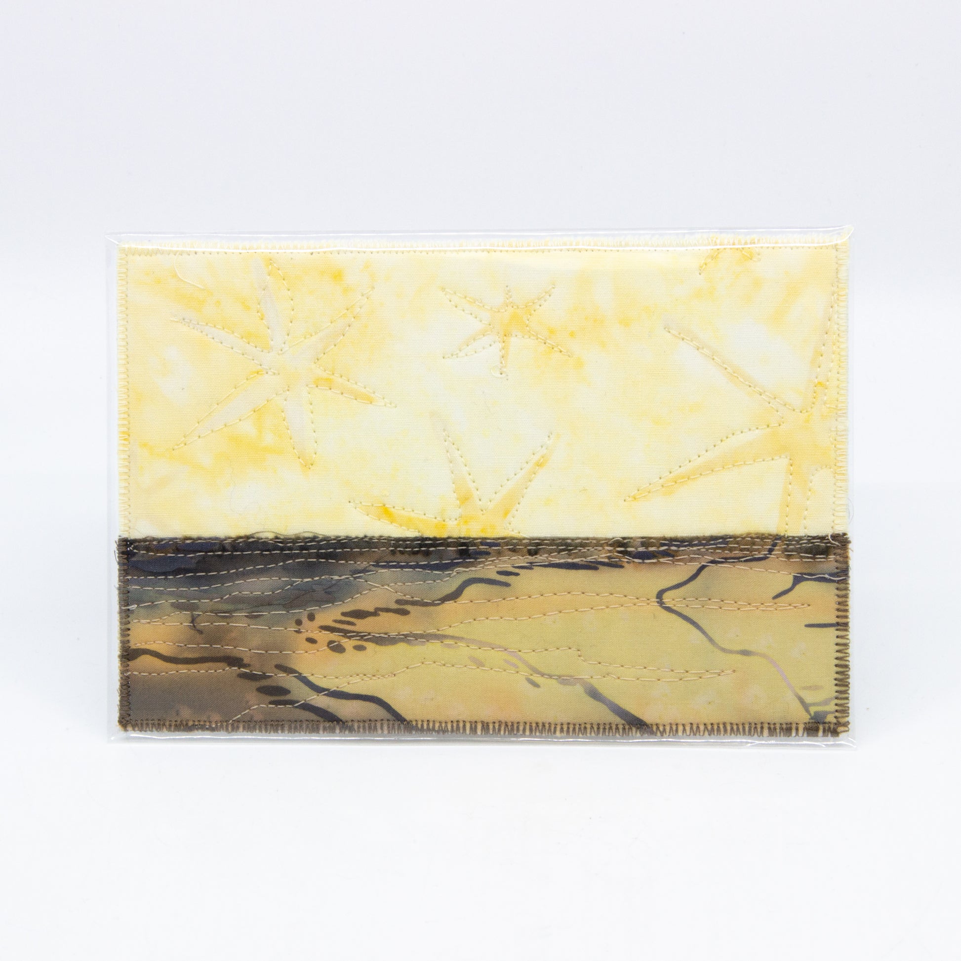 Mini art quilt of a prairie: yellow sky with stars, brown fields
