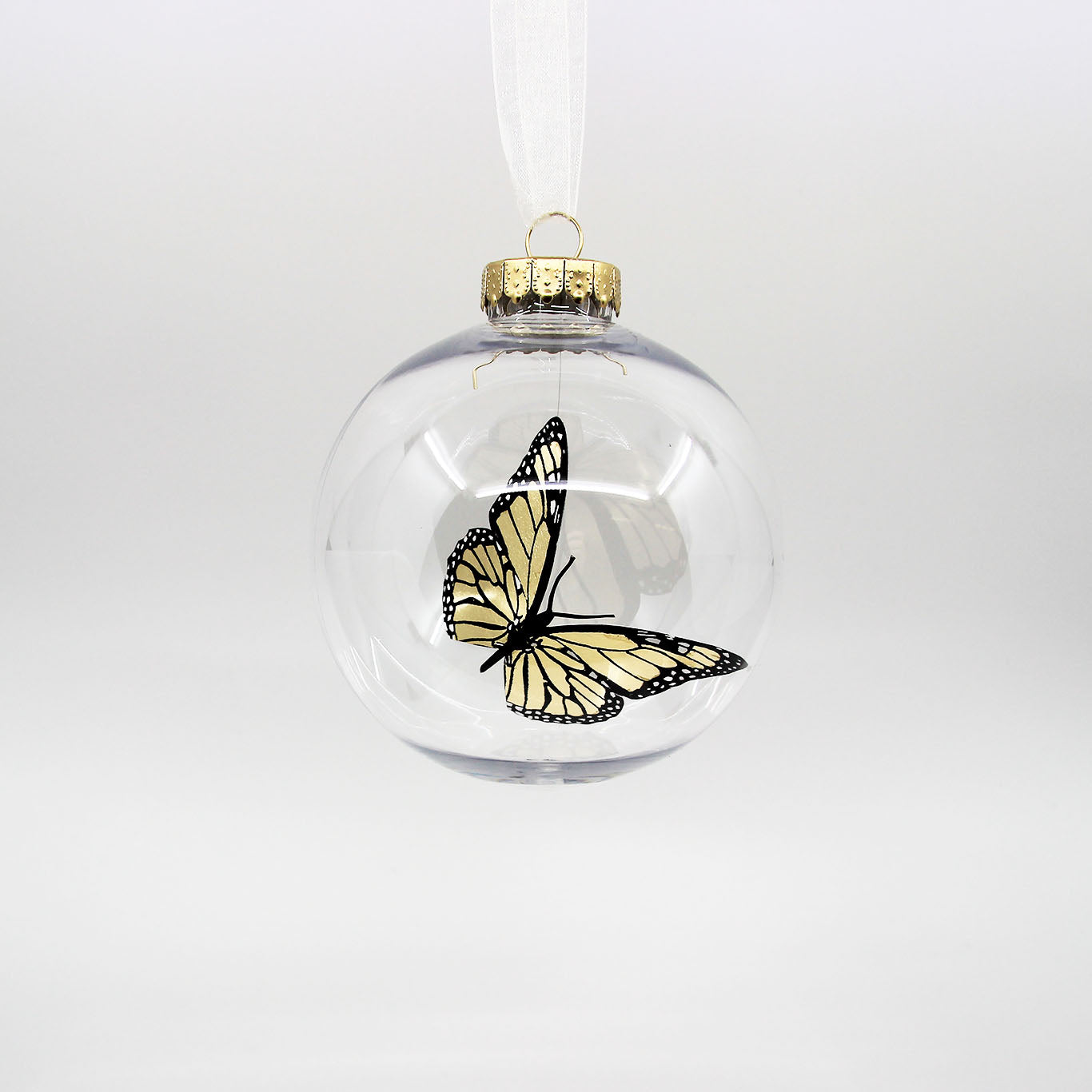 Golden monarch butterfly in a clear Christmas bauble