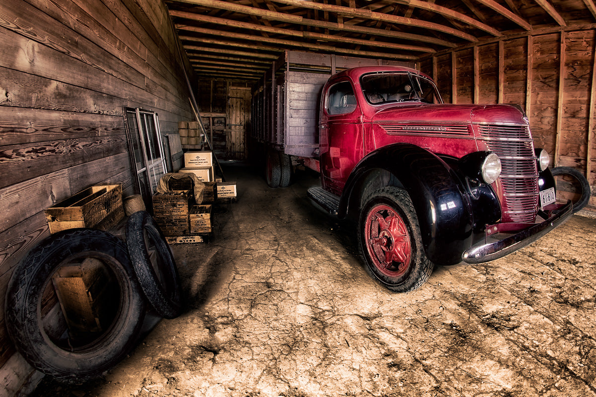 Photograph of a red old fashioned tractor in a wood garage