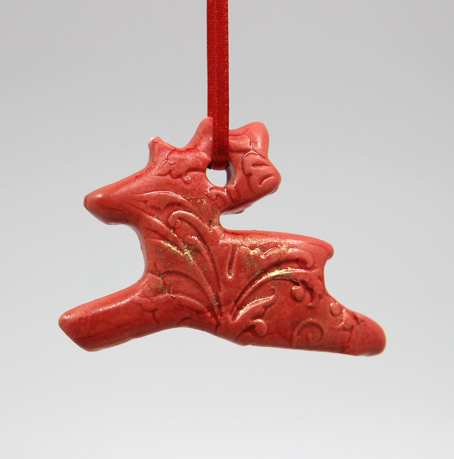 Red reindeer embossed with floral pattern and dusted with gold