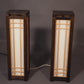 Two wooden lamps with glass panels on a gray background