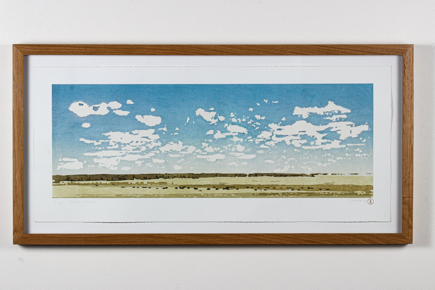 Framed wood print of a landscape with blue sky and white clouds