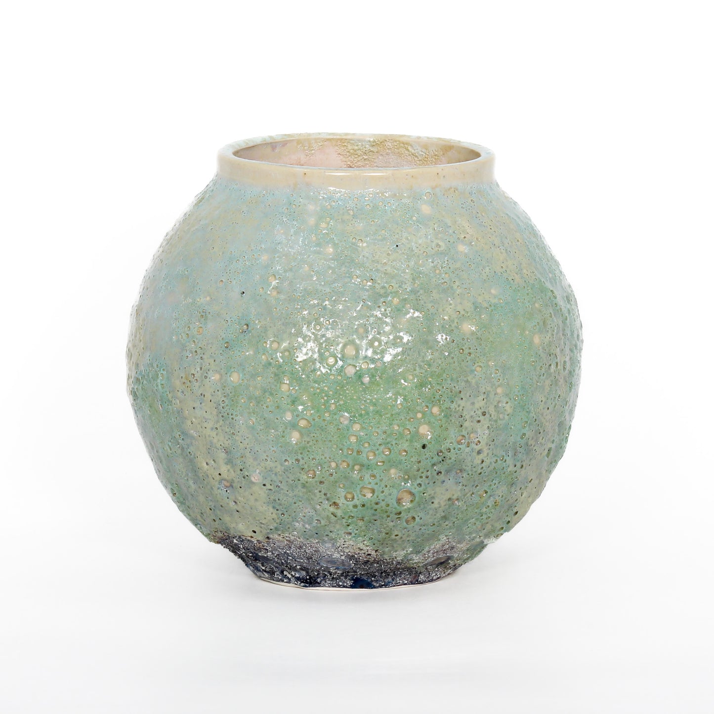 A round ceramic vessel. Glaze is bubbly and textured. Beige at top, mint green in middle, dark blue at bottom.