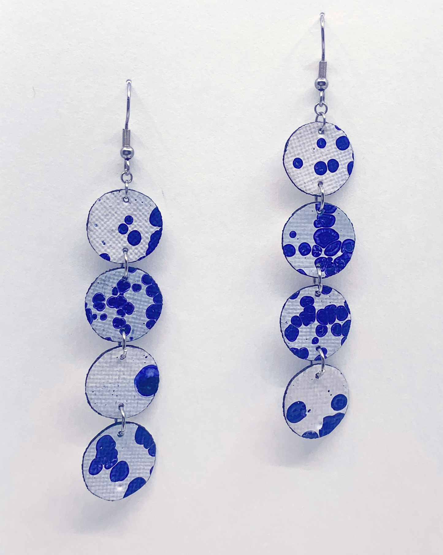 Earrings with blue and white circular patterns on a light gray background