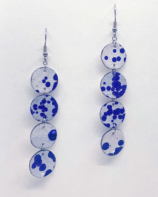 Earrings with blue and white circular patterns on a light gray background