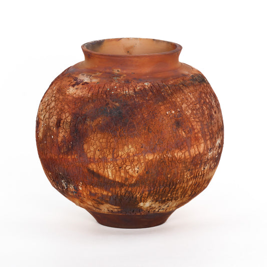 A round ceramic vessel. Surface is textured, with rust brown and orange crackly splotches.