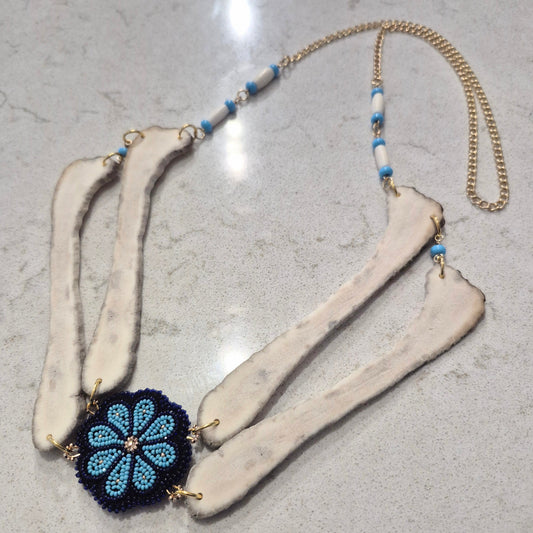 Beaded necklace with floral pendant and antlers on a textured surface