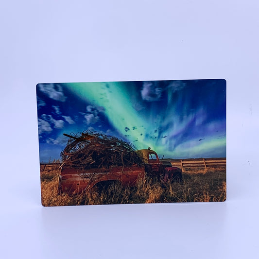 Rusted truck in a field with a vibrant Northern Lights sky