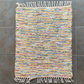 top down view of a colourful woven rug with fringe laying flat on the ground