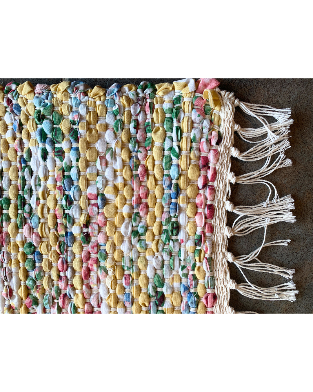 Detail view of a colourful woven rug with fringe 