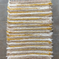 A top down view of a Brown, white and mustard woven fringe rug laying on the floor