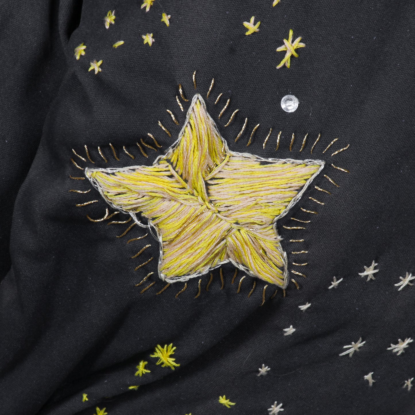 A close up photo of a large star embroidered in yellow and white on navy fabric.