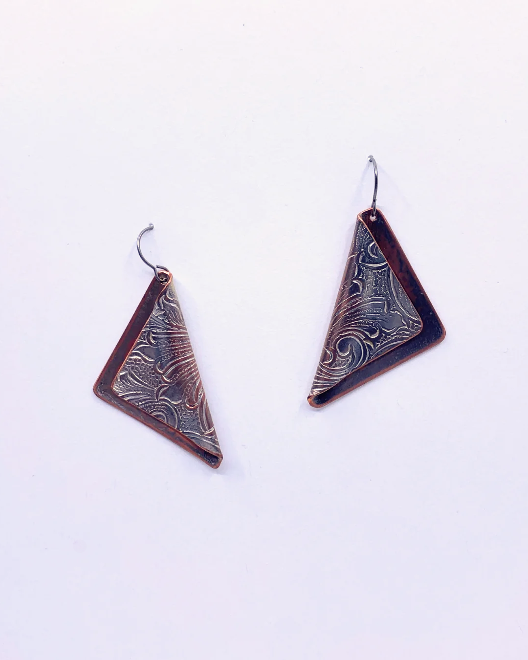 A pair of triangular drop earrings with a dark reddish-brown frame and a textured, patterned silver-toned center, hanging from simple metal fishhook wires on a plain white background.